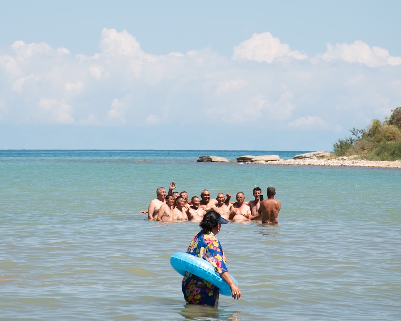 une femme se baigne avec une bouée dans l'Yssk-Koul devant un groupe d'hommes